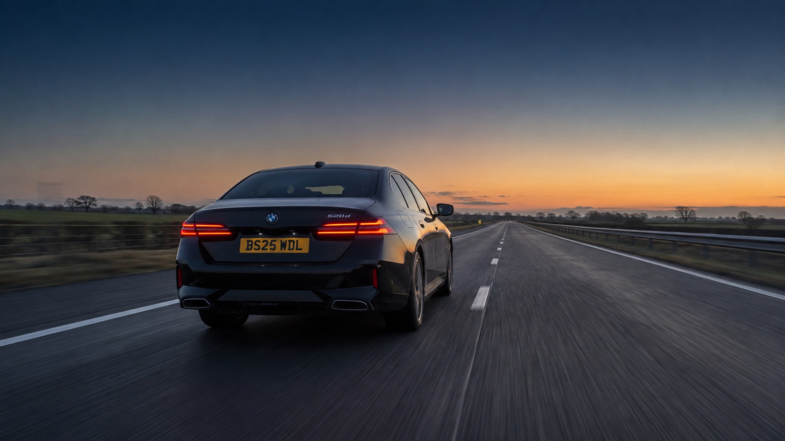 Black BMW 5 Series on a UK motorway at dawn during a Blackpool to Manchester Airport transfer