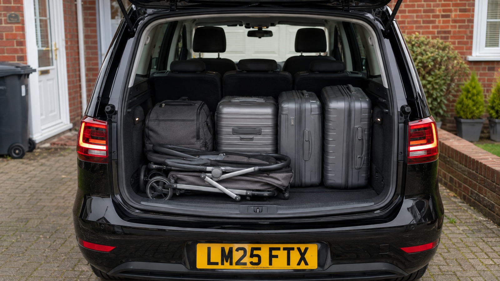 Open boot of a black VW Sharan with a folded buggy loaded alongside suitcases