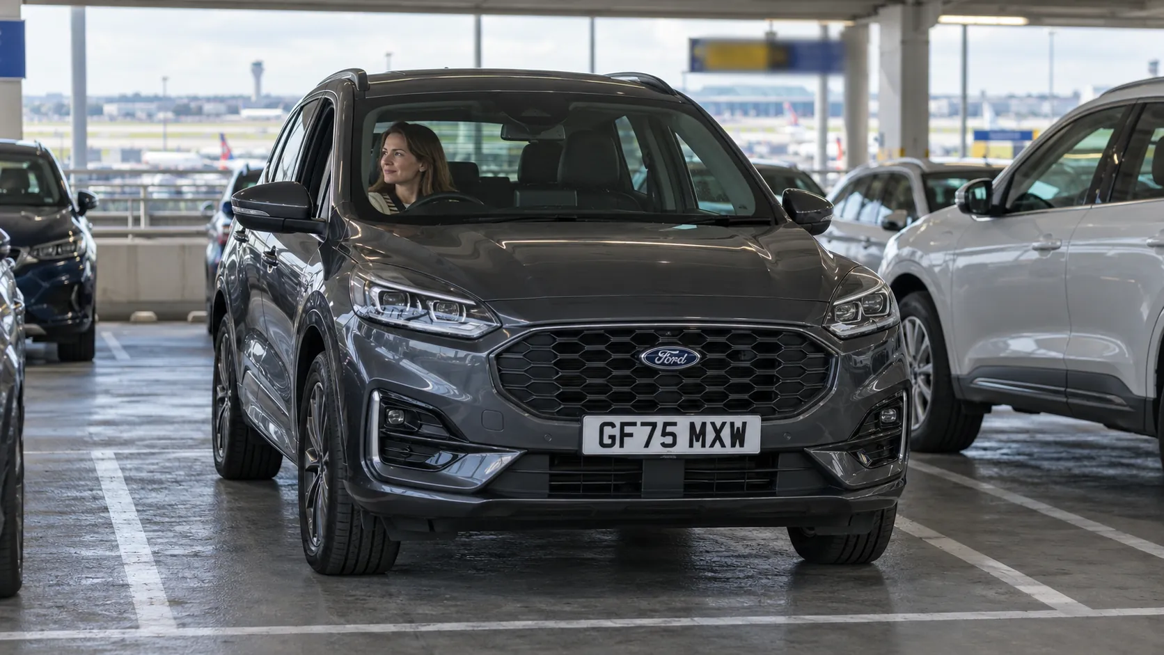 Woman waiting in her dark grey car in the Express Pick-Up bays at Gatwick North Terminal